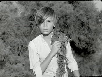 Movie still from “White Mane” (1953), directed by Albert Lamorisse – A young woman holding a piece of string in her hand; Medium shot, High angle