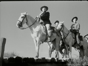 Movie still from “White Mane” (1953), directed by Albert Lamorisse – A group of men riding on the backs of horses; Wide shot, Low angle