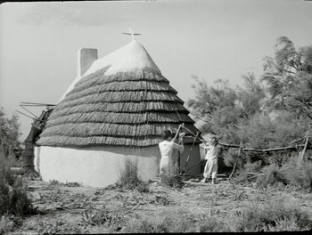 Movie still from “White Mane” (1953), directed by Albert Lamorisse – A person standing next to a hut in a field; Wide shot, Low angle