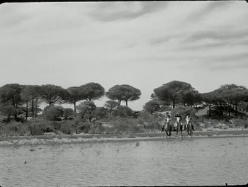 Movie still from “White Mane” (1953), directed by Albert Lamorisse – A group of people riding horses across a body of water; Extreme Wide shot, Low angle