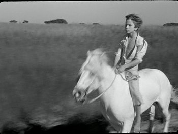 Movie still from “White Mane” (1953), directed by Albert Lamorisse – A young boy riding a white horse through a field; Medium shot, High angle