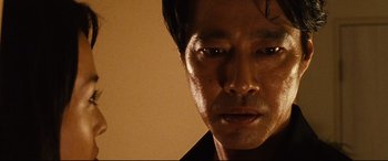 Movie still from “Why Don't You Play in Hell?” (2013), directed by Sion Sono – A man's face in a dark room; Extreme Close Up shot, Low angle
