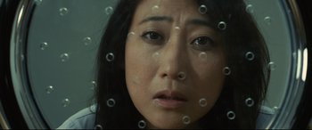 Movie still from “Why Don't You Play in Hell?” (2013), directed by Sion Sono – A woman's face through a glass; Close Up shot, High angle