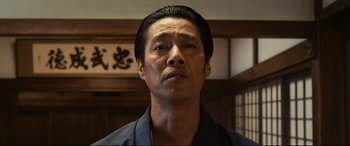 Movie still from “Why Don't You Play in Hell?” (2013), directed by Sion Sono – A person wearing a black shirt; Close Up shot, Low angle