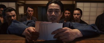 Movie still from “Why Don't You Play in Hell?” (2013), directed by Sion Sono – A group of men standing next to each other holding papers; Close Up shot, High angle
