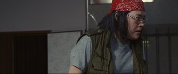 Movie still from “Why Don't You Play in Hell?” (2013), directed by Sion Sono – A man with long black hair wearing a red bandanna; Close Up shot, Over the shoulder angle