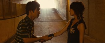 Movie still from “Why Don't You Play in Hell?” (2013), directed by Sion Sono – A man and a woman shaking hands in a tunnel; Medium shot, Over the shoulder angle