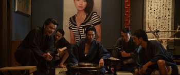 Movie still from “Why Don't You Play in Hell?” (2013), directed by Sion Sono – A group of people sitting around a table; Medium shot, High angle