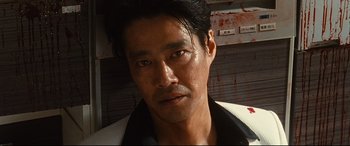 Movie still from “Why Don't You Play in Hell?” (2013), directed by Sion Sono – A person wearing a black and white shirt; Close Up shot, Low angle
