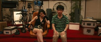 Movie still from “Why Don't You Play in Hell?” (2013), directed by Sion Sono – A man and a woman sitting in a chair; Medium shot, Low angle
