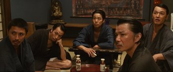 Movie still from “Why Don't You Play in Hell?” (2013), directed by Sion Sono – A group of men sitting around a table; Medium shot, High angle