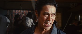 Movie still from “Why Don't You Play in Hell?” (2013), directed by Sion Sono – An asian man with his mouth wide open; Close Up shot, Low angle