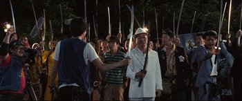 Movie still from “Why Don't You Play in Hell?” (2013), directed by Sion Sono – A group of people holding swords in front of a crowd; Medium shot, High angle