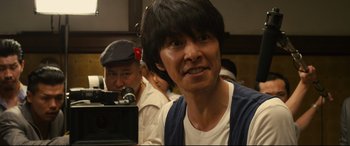 Movie still from “Why Don't You Play in Hell?” (2013), directed by Sion Sono – A man with a beard and a hat is looking at the camera; Close Up shot, Low angle