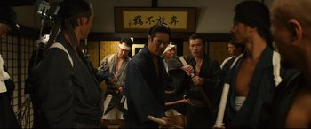 Movie still from “Why Don't You Play in Hell?” (2013), directed by Sion Sono – A group of men in traditional japanese garb holding wooden sticks; Medium shot, High angle