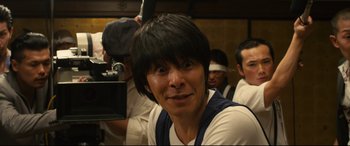 Movie still from “Why Don't You Play in Hell?” (2013), directed by Sion Sono – A man in a white shirt and black hair; Close Up shot, Low angle