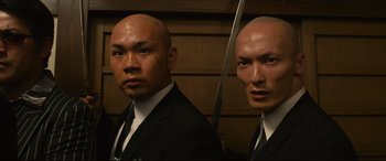Movie still from “Why Don't You Play in Hell?” (2013), directed by Sion Sono – Two men in suits and ties holding a sword; Close Up shot, Low angle