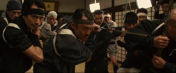 Movie still from “Why Don't You Play in Hell?” (2013), directed by Sion Sono – A group of men in traditional japanese garb; Medium shot, Low angle