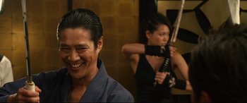 Movie still from “Why Don't You Play in Hell?” (2013), directed by Sion Sono – A man and a woman in a room with a mirror; Close Up shot, Over the shoulder angle