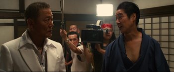 Movie still from “Why Don't You Play in Hell?” (2013), directed by Sion Sono – A group of people standing in front of a camera; Medium shot, Low angle