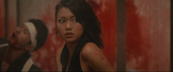 Movie still from “Why Don't You Play in Hell?” (2013), directed by Sion Sono – A woman with blood all over her face and shoulder; Close Up shot, Over the shoulder angle