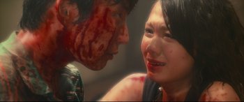 Movie still from “Why Don't You Play in Hell?” (2013), directed by Sion Sono – A woman with blood all over her face and neck; Close Up shot, Over the shoulder angle