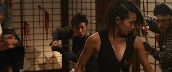 Movie still from “Why Don't You Play in Hell?” (2013), directed by Sion Sono – A man and a woman are fighting in a room; Medium shot, Over the shoulder angle