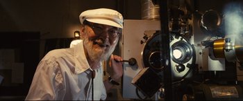 Movie still from “Why Don't You Play in Hell?” (2013), directed by Sion Sono – An older man wearing a white hat and glasses; Close Up shot, Low angle