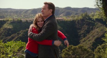 A man and a woman hugging on top of a hill