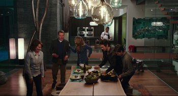 Movie still from “Why Him?” (2016), directed by John Hamburg – A group of people standing around a table with food on top of it; Wide shot, High angle