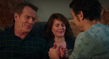 Movie still from “Why Him?” (2016), directed by John Hamburg – Two men and a woman sitting next to each other on a couch; Medium shot, Over the shoulder angle