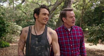 Movie still from “Why Him?” (2016), directed by John Hamburg – A man standing next to another man with tattoos on his arms; Medium shot, Over the shoulder angle