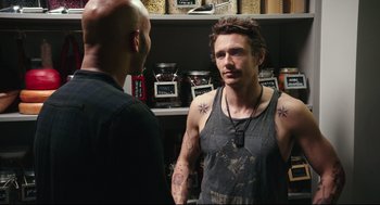 Movie still from “Why Him?” (2016), directed by John Hamburg – A man with tattoos talking to another man in a store; Medium shot, Over the shoulder angle