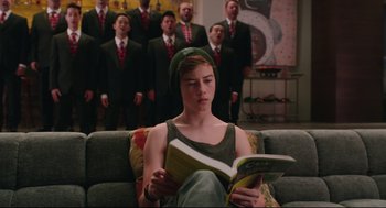 Movie still from “Why Him?” (2016), directed by John Hamburg – A person sitting on a couch reading a book; Medium shot, Over the shoulder angle