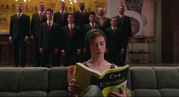 Movie still from “Why Him?” (2016), directed by John Hamburg – A man reading a book in front of a group of men; Medium shot, Over the shoulder angle