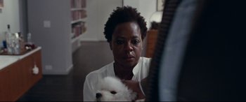 Movie still from “Widows” (2018), directed by Steve McQueen – A woman holding a white dog in her arms; Close Up shot, Over the shoulder angle
