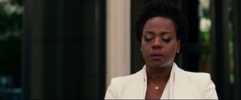 Movie still from “Widows” (2018), directed by Steve McQueen – A woman in a white jacket is looking down at her face; Close Up shot, Over the shoulder angle