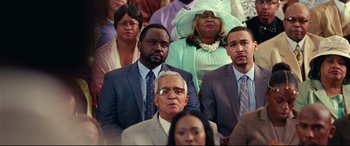 Movie still from “Widows” (2018), directed by Steve McQueen – A group of men and women in suits and hats; Medium shot, Over the shoulder angle