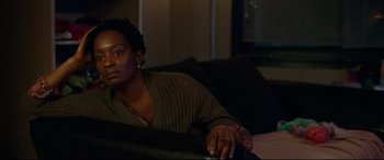 Movie still from “Widows” (2018), directed by Steve McQueen – A woman sitting on a couch in a living room; Medium shot, Over the shoulder angle