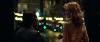 Movie still from “Widows” (2018), directed by Steve McQueen – A man and a woman standing next to each other in front of lights; Medium shot, Over the shoulder angle