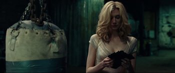 Movie still from “Widows” (2018), directed by Steve McQueen – A woman in a white dress is holding a gun in her hand; Close Up shot, Over the shoulder angle