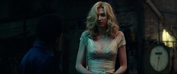 Movie still from “Widows” (2018), directed by Steve McQueen – A woman in a silver dress is standing in front of a wall; Medium shot, Over the shoulder angle