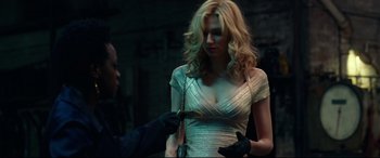 Movie still from “Widows” (2018), directed by Steve McQueen – A woman in a silver dress holding a purse; Medium shot, Over the shoulder angle