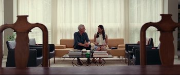 Movie still from “Widows” (2018), directed by Steve McQueen – A man and a woman sitting on a couch talking to each other; Wide shot, Over the shoulder angle