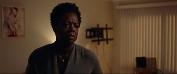 Movie still from “Widows” (2018), directed by Steve McQueen – A woman in a gray sweater is sitting in a living room; Close Up shot, Over the shoulder angle
