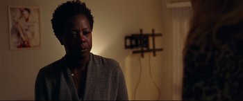 Movie still from “Widows” (2018), directed by Steve McQueen – A woman sitting in front of a wall with wires hanging on the wall; Close Up shot, Over the shoulder angle
