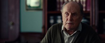 Movie still from “Widows” (2018), directed by Steve McQueen – An older man sitting in front of a book case; Close Up shot, Low angle