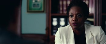 Movie still from “Widows” (2018), directed by Steve McQueen – A woman in a white jacket sitting in a room; Close Up shot, Over the shoulder angle