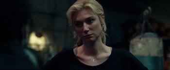 Movie still from “Widows” (2018), directed by Steve McQueen – A woman with blonde hair wearing a black shirt and a gold cross necklace; Close Up shot, Over the shoulder angle