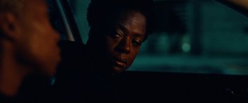 Movie still from “Widows” (2018), directed by Steve McQueen – A person sitting in a car looking at the camera; Close Up shot, High angle